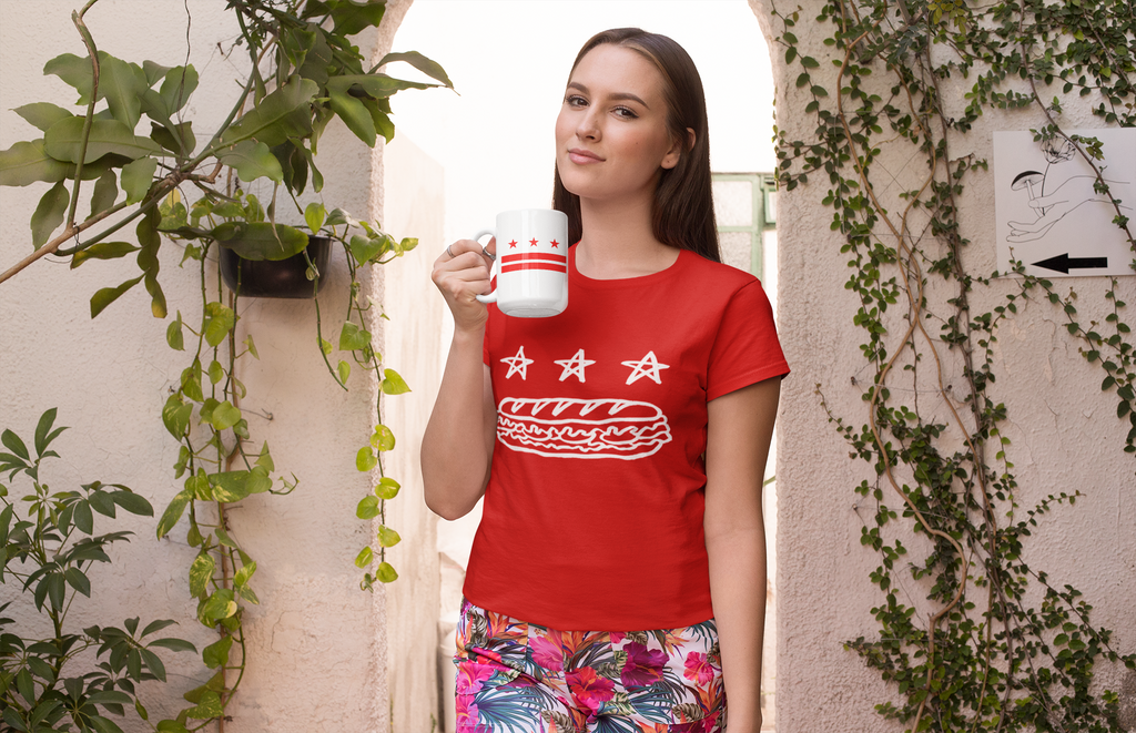 Woman wearing a red free dc sandwich t-shirt holding a white mug with the washington, district of columbia flag on it.